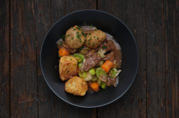 A low calorie Food Fit meal containing beef stew in a black bowl.