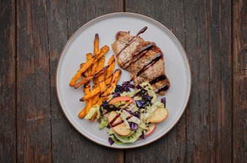 A high protein Food Fit meal containing pork, sweet potato fries, and salad, on a light blue plate.