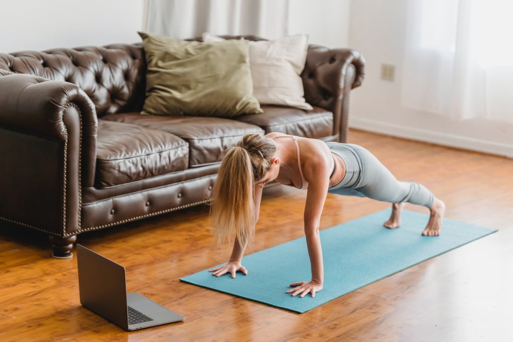 Lady staying fit at home by doing an ab workout on a blue yoga mat.