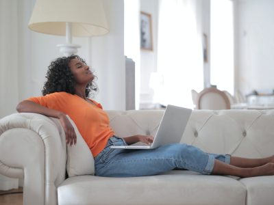 Lady relaxing on a sofa with a laptop on her lap signals the importance of virtual wellness.
