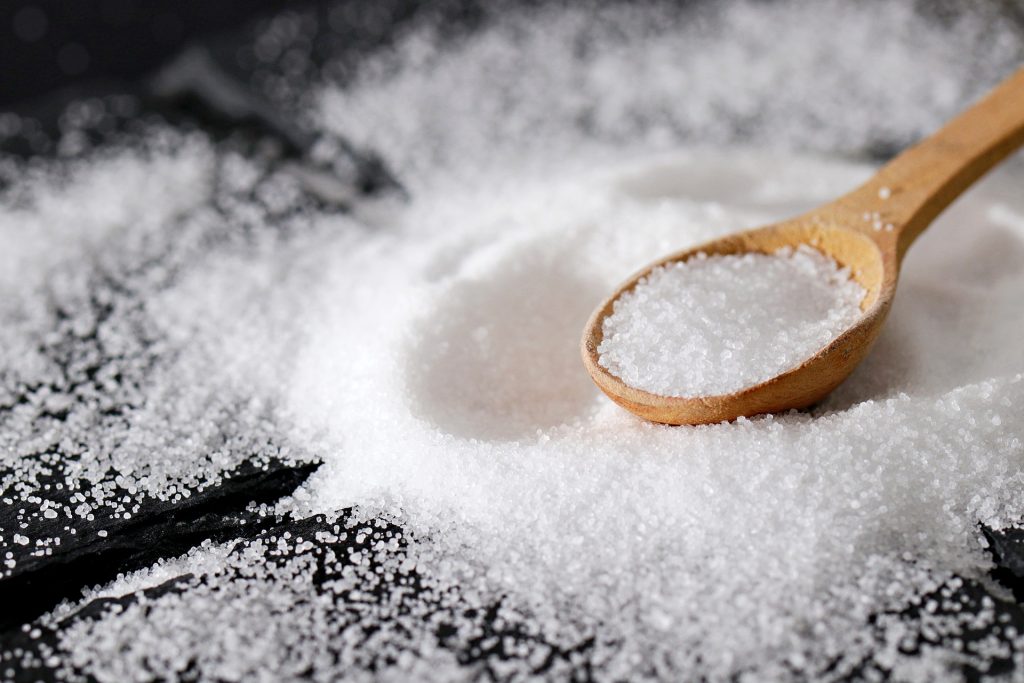 Wooden spoon surrounded by salt implying to eat less salt.