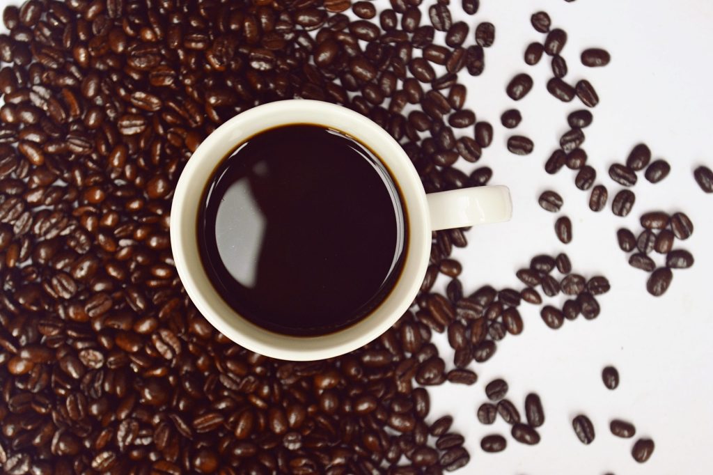 A cup of coffee surrounded by coffee beans illustrates the health benefits of coffee.