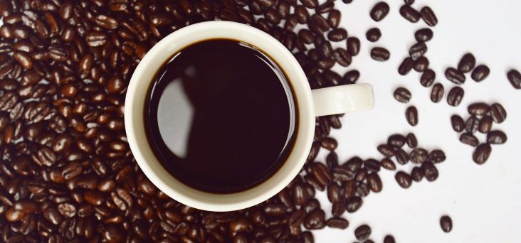 A cup of coffee surrounded by coffee beans illustrates the health benefits of coffee.