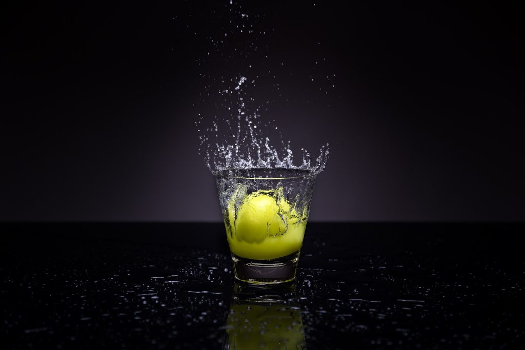 Green apple dropped into a cup, with water splashing out of it on a black background, demonstrates whether intermittent fasting is good for the body.