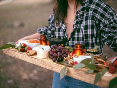 Healthy snacks for weight loss being carried on a wooden tray by a lady in a chequered shirt.
