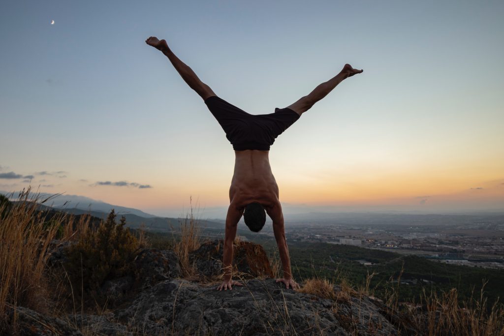 Man doing calisthenics outside on a rcok with a sunset in the background