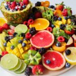 A wooden plate filled with a large variety of fruit that help with muscle growth